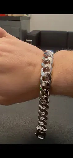 Chunky polished silver curb-link bracelet with a rectangular clasp worn on a wrist